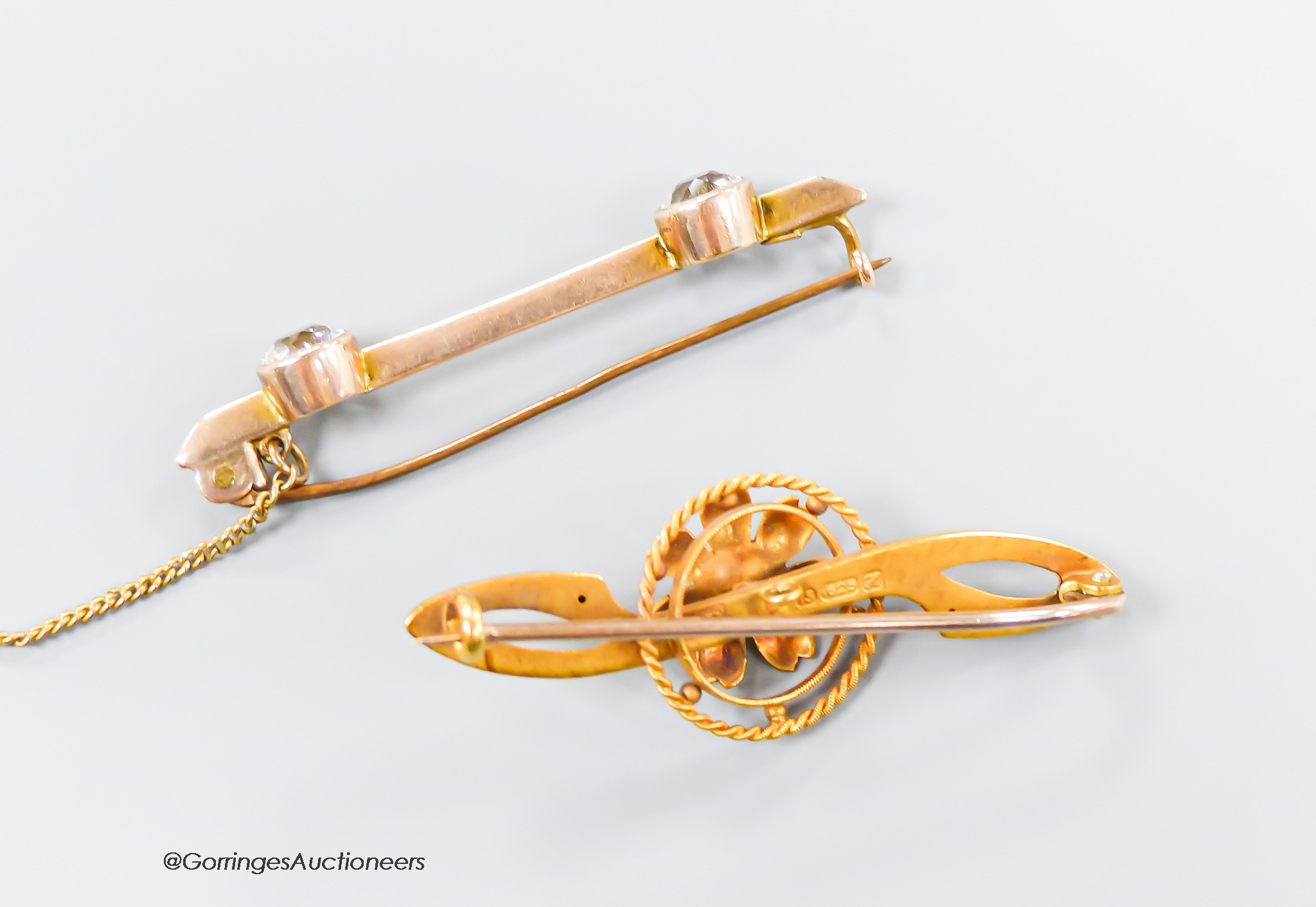 An Edwardian 15ct gold and sapphire set flower head bar brooch, 41mm, gross 2.6 grams and a 9ct and two stone paste set bar brooch, gross 2.6 grams.